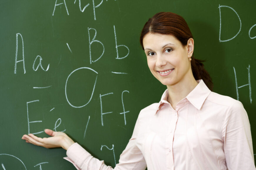 smiling teacher with blackboard background scaled 1 На повестке дня латиница