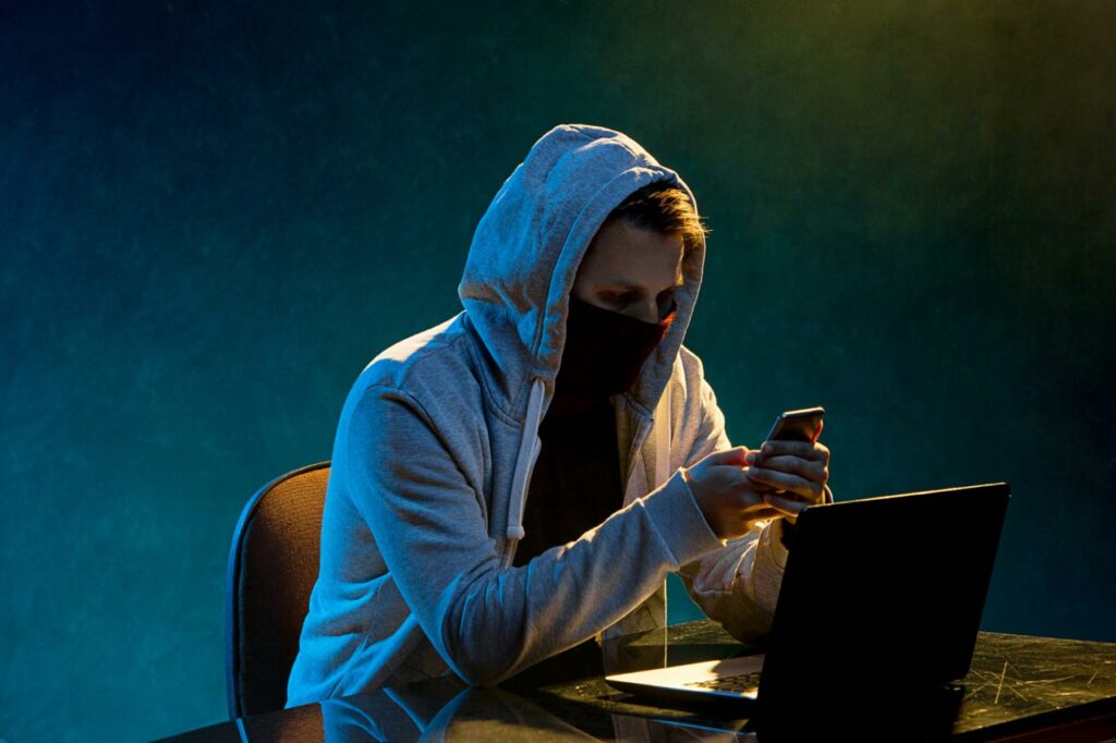 hooded computer hacker stealing information with laptop Алаяқтардан абай болыңыздар!